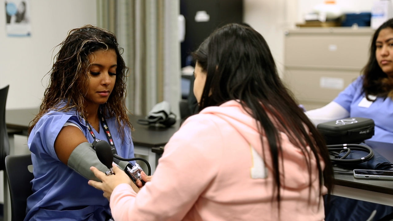 Healthcare worker checks blood pressure in classroom setting
